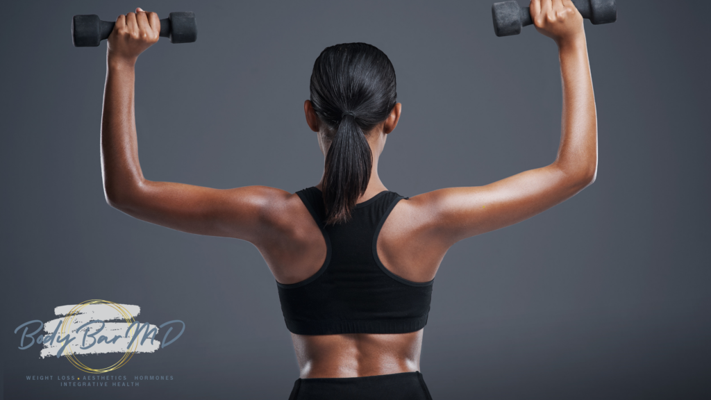 Back view of a woman lifting dumbbells with toned arms, showcasing strength and fitness, featuring the Body Bar MD logo.