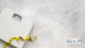 A white bathroom scale with a yellow measuring tape coiled on top, placed on a light gray textured background.