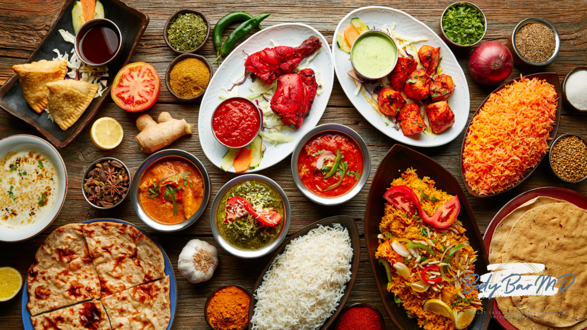 A vibrant spread of colorful Indian dishes, including curries, rice, naan, and spices, displayed on a rustic wooden table.