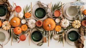 Thanksgiving table setting with pumpkins, greenery, candles, and earthy-toned tableware.