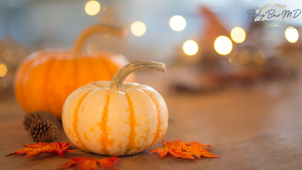 Small decorative pumpkins and autumn leaves with warm bokeh lights in the background, creating a cozy Thanksgiving atmosphere