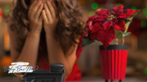 Stressed woman covering her face, seated next to holiday decor, symbolizing holiday stress and its effects on skin.