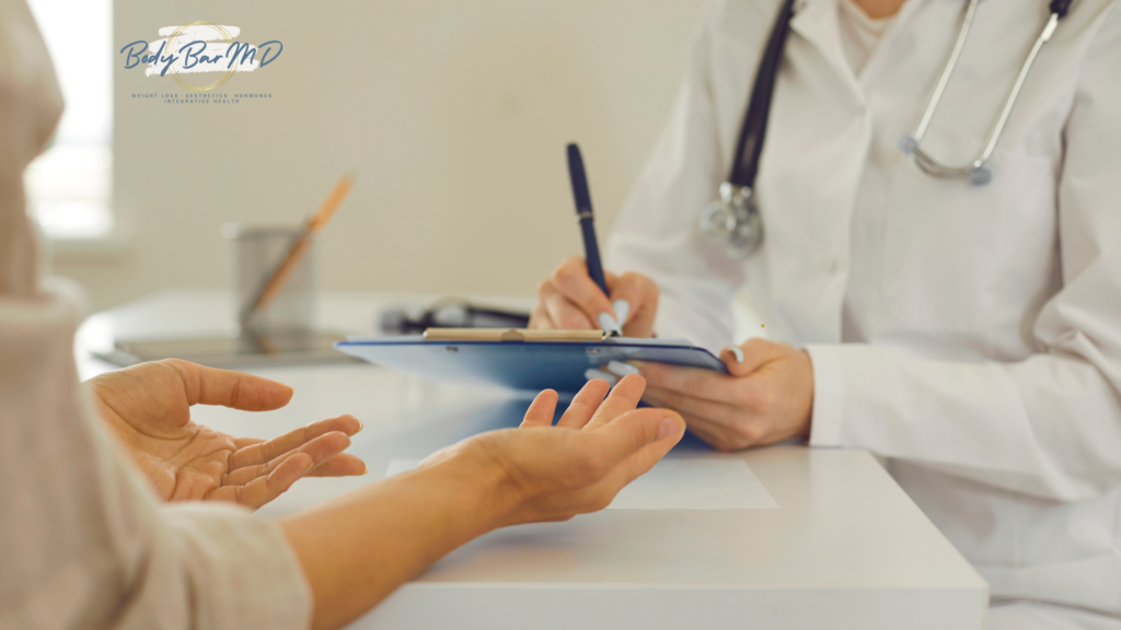 A patient consulting with a doctor who is taking notes on a clipboard during a medical appointment.