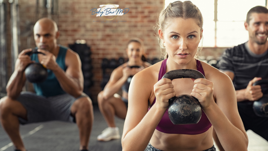 A group fitness class with participants performing kettlebell squats, focusing on strength and endurance.