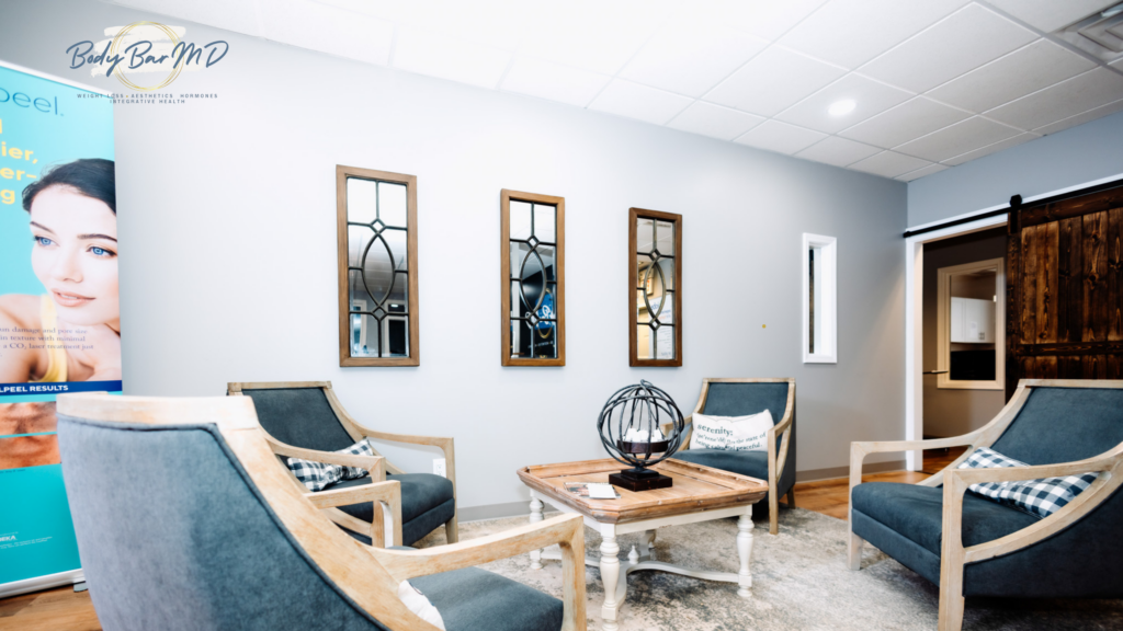 A cozy waiting area at Body Bar MD with elegant chairs, mirrors, and a wooden coffee table.