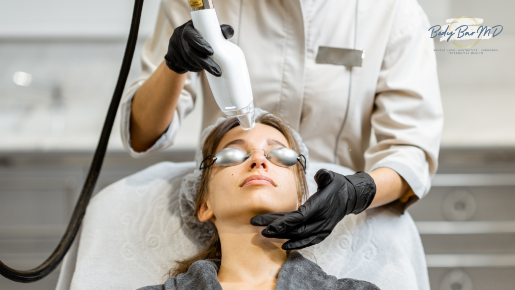 A woman undergoing a professional laser skin treatment wearing protective goggles, administered by a technician in gloves.