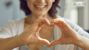 Smiling woman forming a heart shape with her hands, symbolizing heart health and self-love. The Body Bar MD logo is visible in the corner.