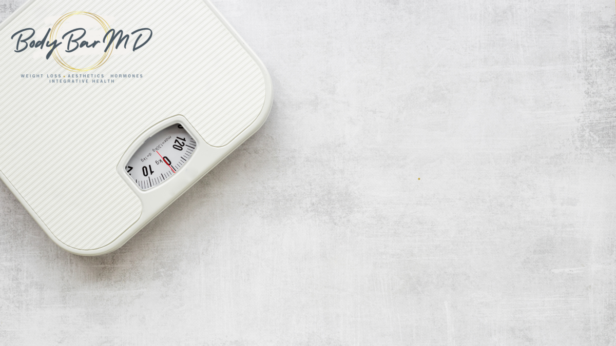 A white bathroom scale on a light gray textured background, symbolizing weight and health focus.