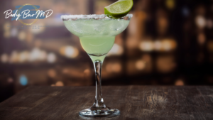 A refreshing margarita with a salted rim and lime garnish served in a classic margarita glass on a wooden table.