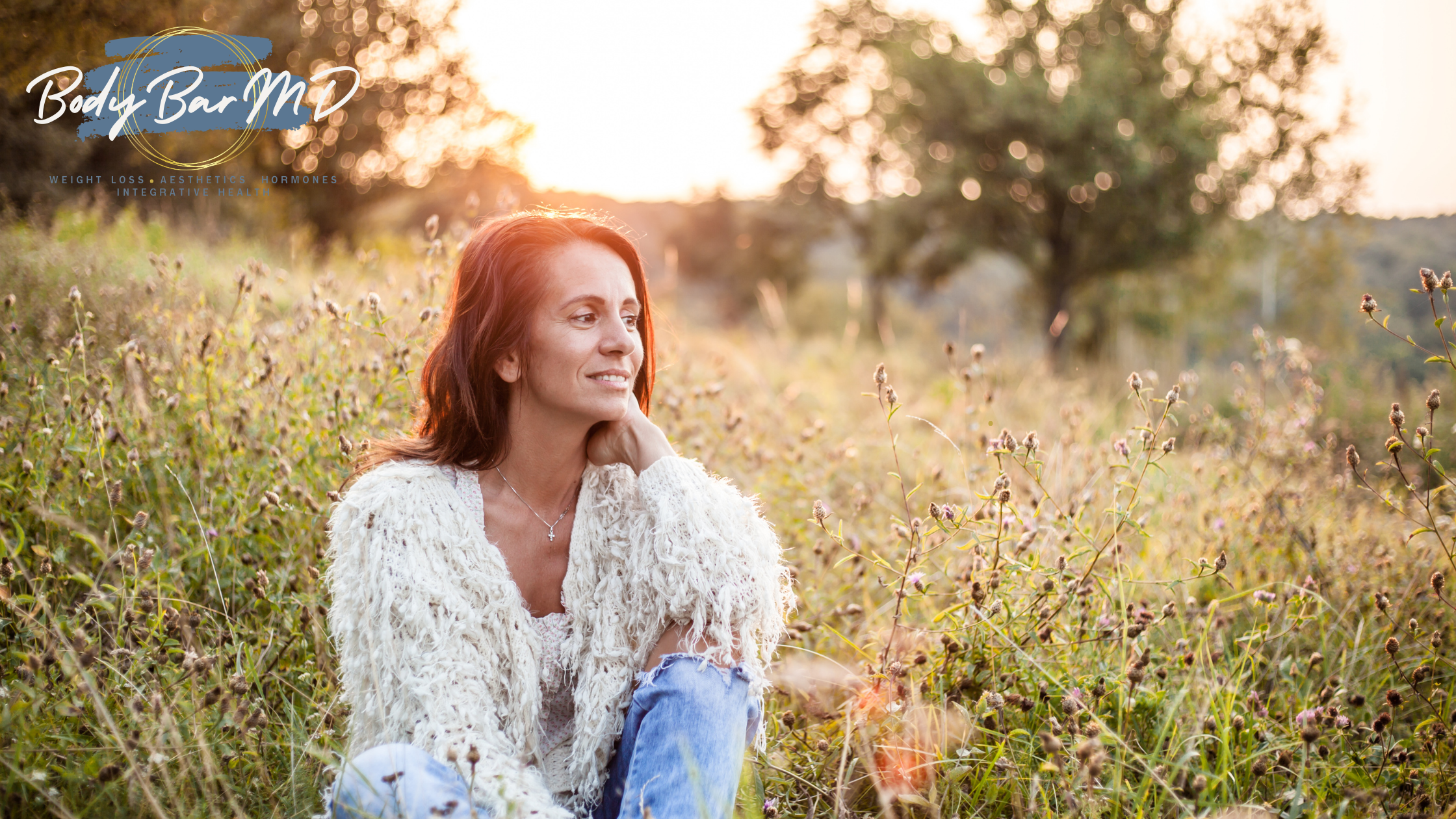A woman sitting in a field contemplates sun damage treatment in Indianapolis, IN